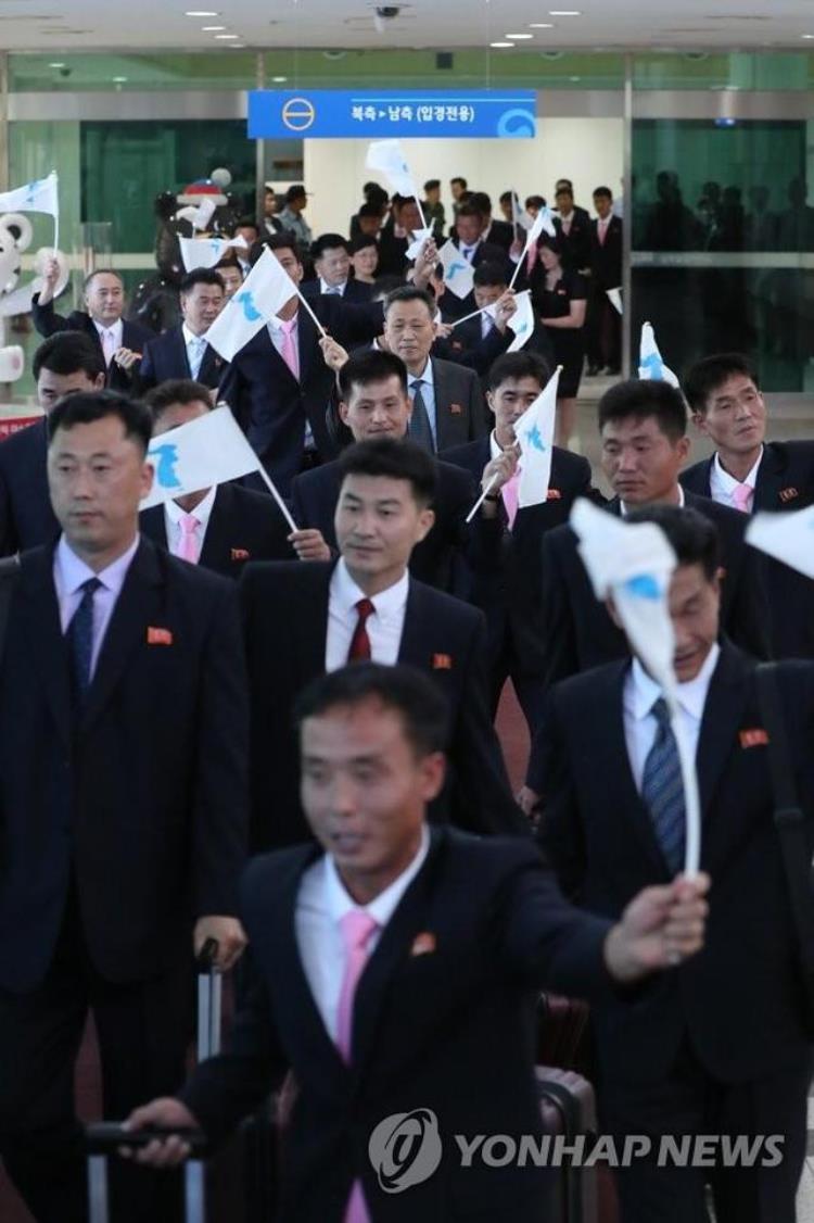 朝鲜工人足球队抵达韩国举统一旗戴领袖徽章